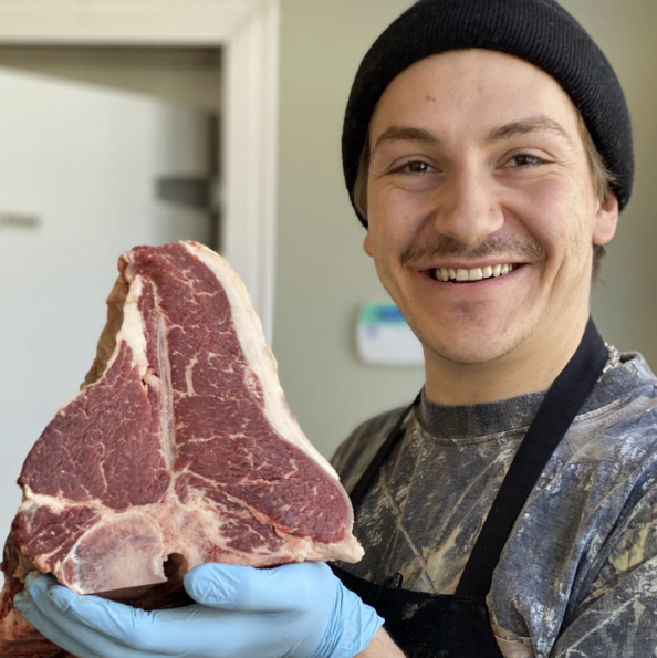 Osprey's Roost butcher holding up a t-bone steak